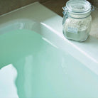 Jar of clay powder on a bathtub with green water